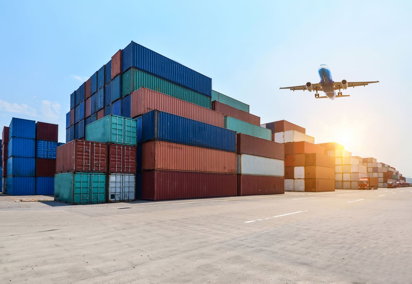 Shipping containers at port with a cargo plane departing overhead, representing international export